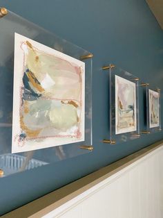 three paintings hang on the wall next to each other in a room with blue walls