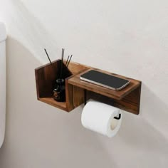 a toilet paper holder is attached to the wall with a phone and other items on it