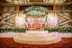 the wedding stage is decorated with flowers and greenery for an elegant touch to the venue