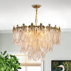 a chandelier hanging from the ceiling in a room with plants and pictures on the wall