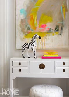 a zebra figurine sitting on top of a white dresser next to a painting