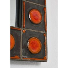 an orange and black square shaped object hanging on the wall