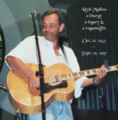 a man holding a guitar while standing next to a microphone