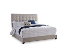 a bed with white linens and blue pillows on it's headboard, in front of a white background