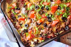 an enchilada casserole with black olives, tomatoes and green onions