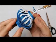 someone is working on something that looks like a blue and white striped ornament