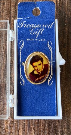 a brooch with the image of elvis presley on it in a blue package, sitting on a wooden table