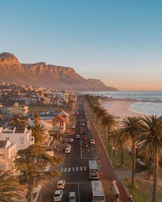 an aerial view of a beach town with mountains in the background and palm trees lining the street