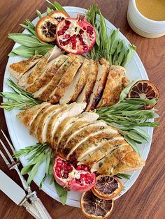 a white plate topped with sliced up meat next to oranges and pomegranate