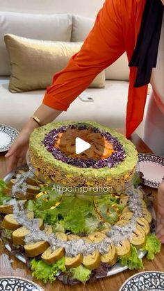 a woman is decorating a large cake on a table with plates and napkins