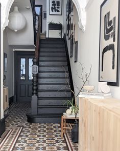 an entry way with black and white tile flooring, stairs and pictures on the wall