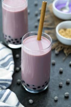 two glasses filled with pink smoothie on top of a table