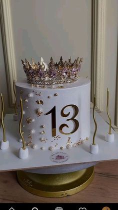 a white cake with gold decorations and a crown on top that reads 13 1 / 2