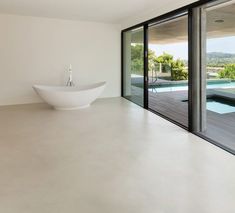 a large white bowl sitting on top of a floor next to a wall filled with windows