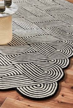 a black and white rug on the floor next to a vase with two glasses in it