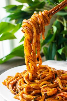 noodles being lifted from a plate with chopsticks