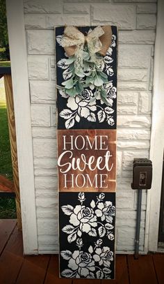 a sign that says home sweet home on the side of a building with flowers and leaves painted on it