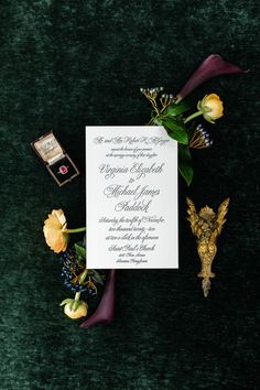 the wedding stationery is laid out on green velvet