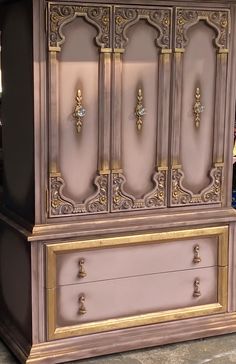 an ornate armoire with gold trim and drawers