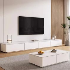 a living room with a large flat screen tv mounted on the wall and white furniture