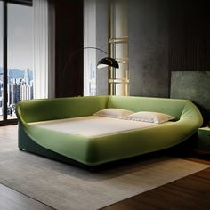 a large green bed sitting on top of a hard wood floor next to a window