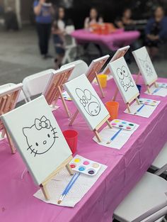 there are three hello kitty paintings on easels at the table with markers and pencils