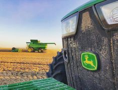 a tractor is driving in the middle of a field with a deer emblem on it