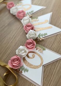 some pink and white flowers are on top of a card with gold foil lettering that says g