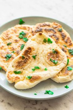 two flatbreads on a white plate with green garnish and parsley