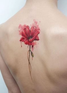 a woman's back with a red flower tattoo on it