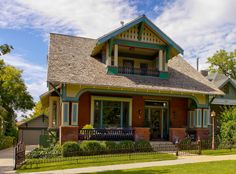 a large house with green trim and blue windows on a sunny day in the suburbs