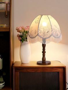 a lamp that is sitting on top of a table next to a vase with flowers in it