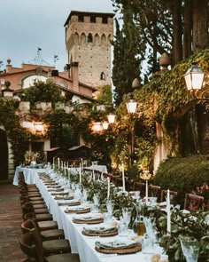 a long table is set with place settings for an outdoor dinner in front of a castle