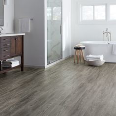 a bathroom with wood flooring and white bathtub next to a stand alone sink