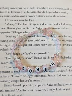 an open book with a bracelet that says love on the front and back of it