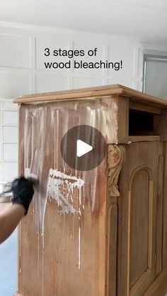 a person painting a wooden cabinet with white paint