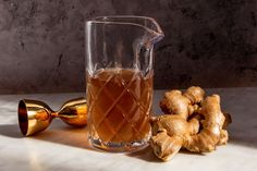 a pitcher of ginger tea next to some ginger roots