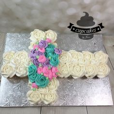 a cake shaped like a cross with flowers on the top and bottom is sitting on a silver platter