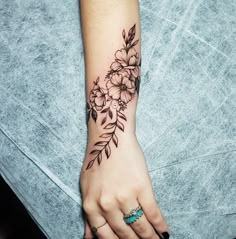 a woman's hand with a flower tattoo on her left arm and the wrist