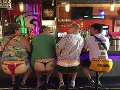 four people sitting at a bar with their backs turned to the same direction as they sit on stools