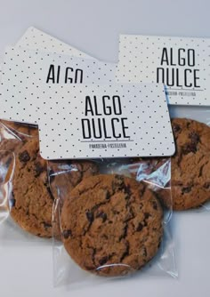 three chocolate chip cookies wrapped in cellophane on top of each other with the words algo dulce printed on them