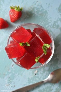 a glass filled with watermelon and ice cubes next to some strawberries