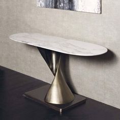 a white marble topped table in front of a gray wall with a painting on it