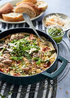 a pan filled with food sitting on top of a table next to bread and salad