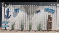 a white picket fence with blue and white signs on the top, along with an anchor