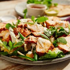 a salad with chicken, lettuce and dressing on it is served in a bowl