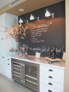 a kitchen with chalkboard on the wall next to drawers and cabinets in front of it