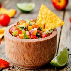 a wooden bowl filled with salsa and chips