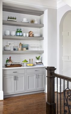 a kitchen with open shelving and wooden floors, white walls and wood flooring