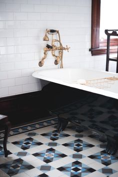 an old fashioned bathtub in a bathroom with black and white tiles